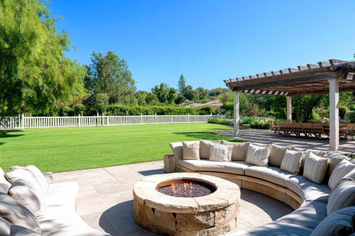 Outdoor fire pit seating area under pergola with patio dining in background