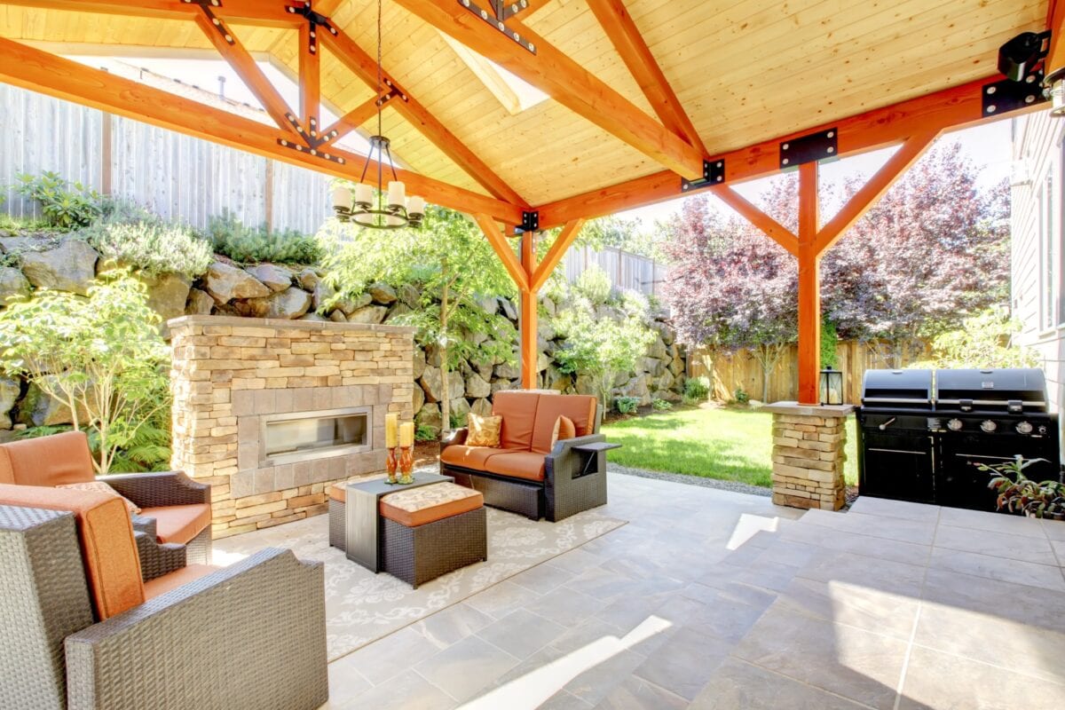 Covered patio with stone fireplace, seating, and outdoor grill