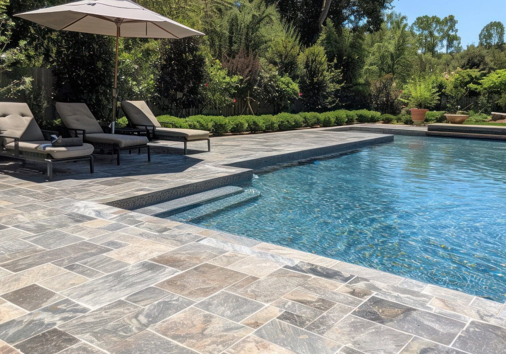 luxury-pool-paver-patio-aldi-va-backyard-upgrade Luxury backyard pool with stone paver patio and lounge chairs in Aldie, VA.